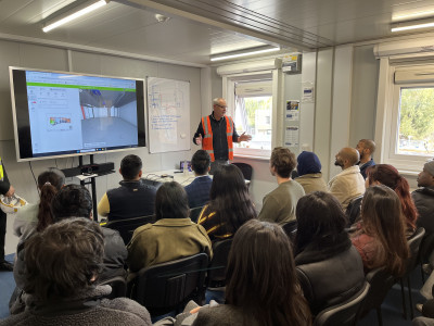 click/tap to enlarge this image... Willmott Dixon engineer and Mr Nawed Khan, Project Director at Queen Mary University of London, explain digital construction processes and project coordination to SEMS students during an indoor project briefing session.
