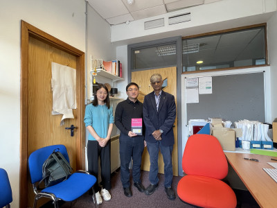 In Harry's office. Professor Wu is holding a copy of 'Phase Transitions' written by Harry and Haixue Yan.