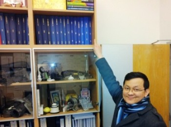 Kartpan adding his final bound thesis to the shelf in James' office.