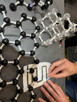 click/tap to enlarge this image... An LED lighting up in a graphene electronic circuit, at New Scientist Live