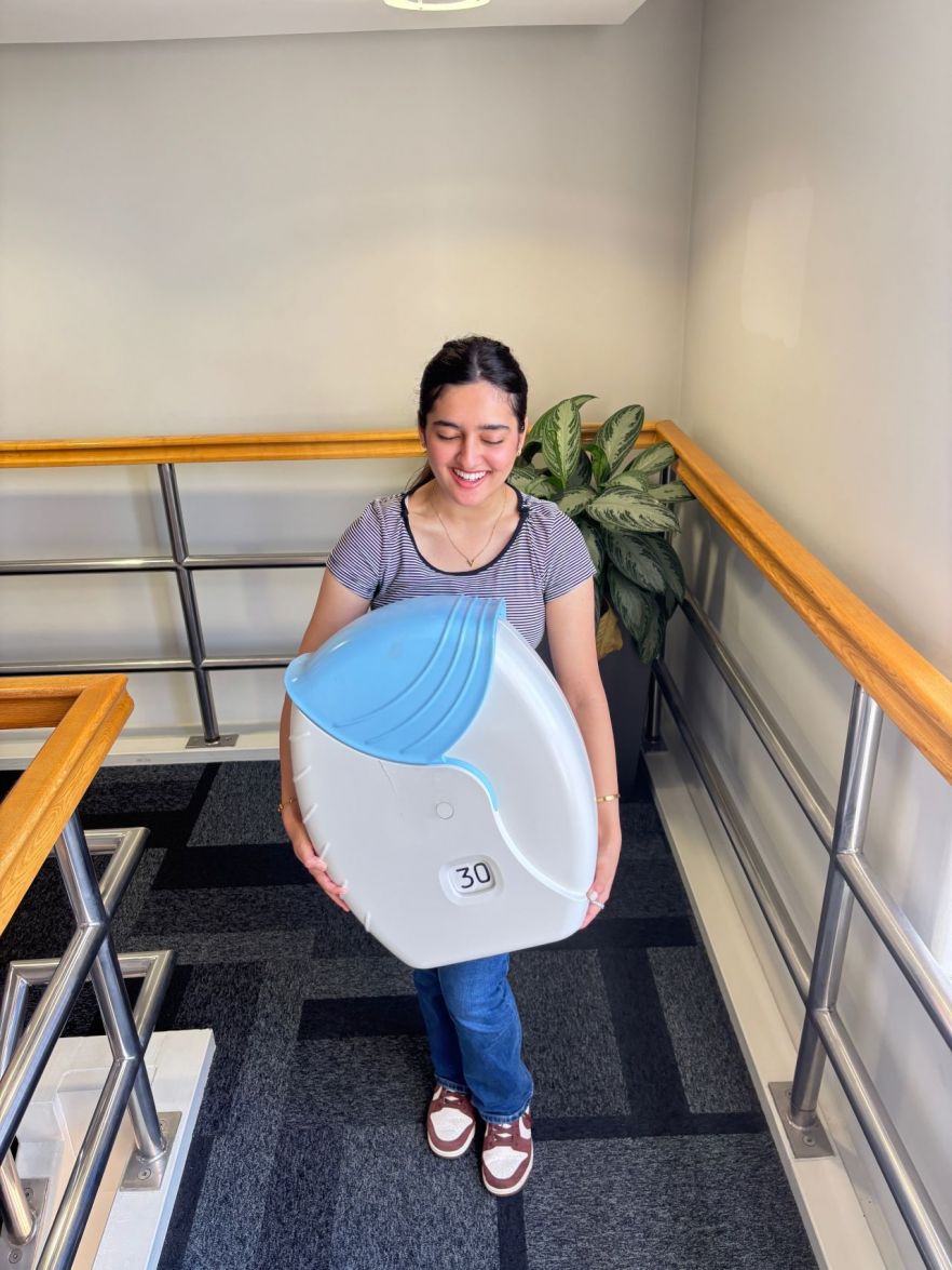 Amna carrying a large piece of equipment, laughing