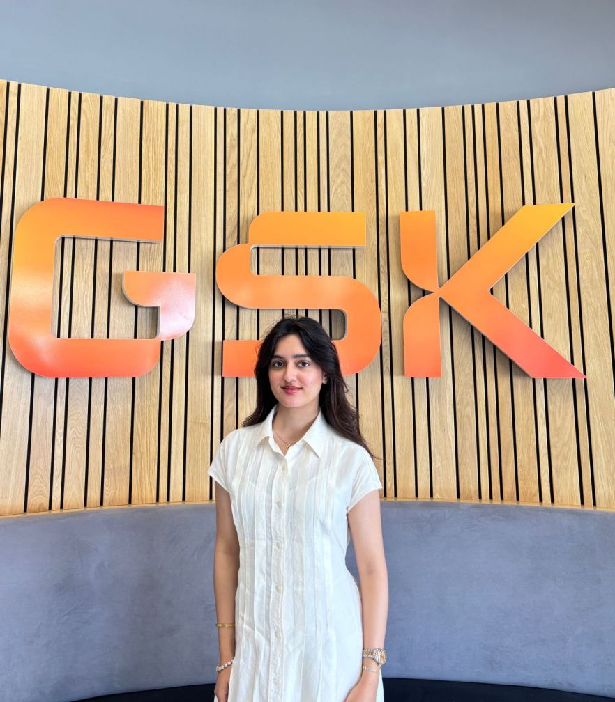 Amna standing in front of a large sign saying 'GSK'