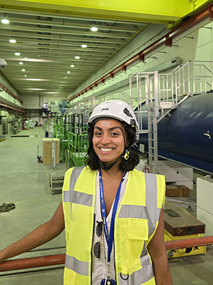 Anika in a high vis jacket and hard hat at her workplace of CERN