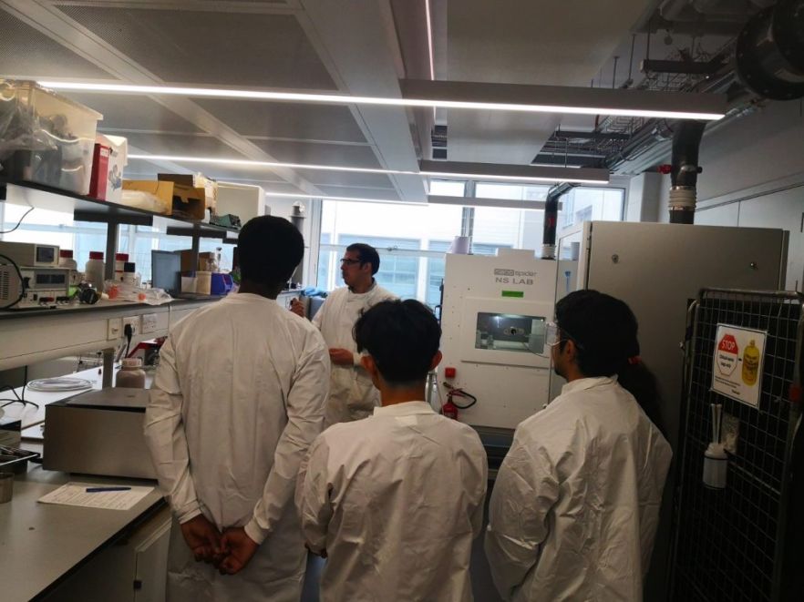 Group of people watching electrospinning in progress in a lab