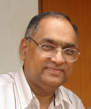 A headshort of Dr Ranjan Vepa, smiling at the camera, wearing glasses and a white shirt